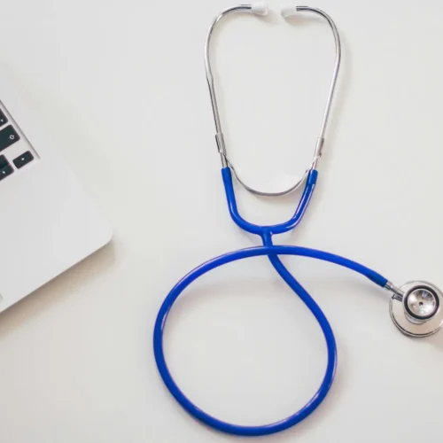 Medical stethoscope and laptop on a white desk, symbolizing digital health solutions.